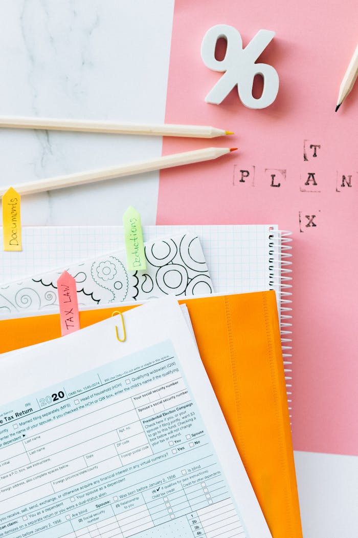 Overhead view of tax documents, percentage sign, and stationery items on pastel paper.